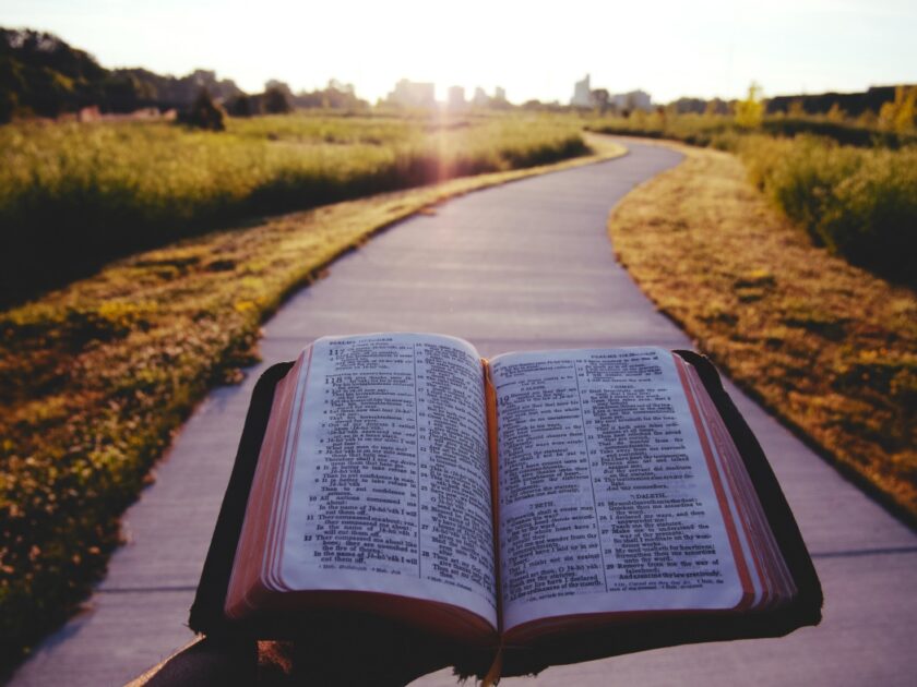 A Christian holding an open bible in front of a pathway