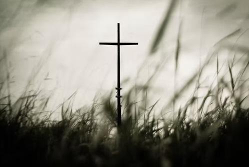 A wooden Christian cross symbol in a grass field.